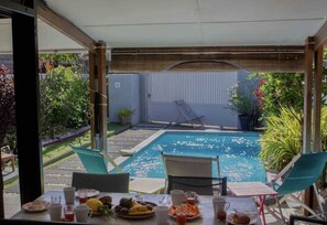 Un espace repas aménagé au bord de la piscine, avec une table pour deux, des chaises et une vue sur la piscine.