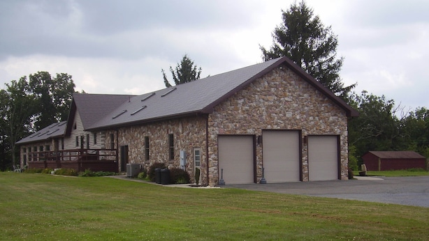 A stone building with a sloped roof and three garage doors. - Working Horse Ranch With Indoor Pool!! (Grantville)