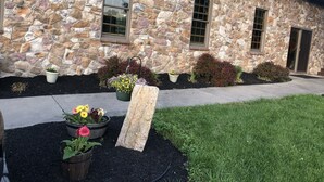 A stone building with a stone facade, multiple windows, and a well-maintained garden with various potted plants and flowers. - Working Horse Ranch With Indoor Pool!! (Grantville)