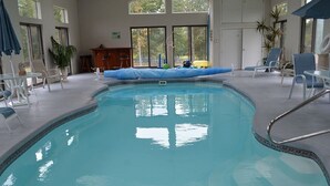 An indoor swimming pool with clear blue water, surrounded by lounge chairs and a sunbed. - Working Horse Ranch With Indoor Pool!! (Grantville)