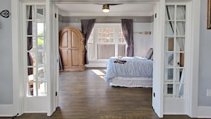 A bedroom with a bed, a wooden wardrobe, and a window with curtains.