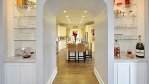A kitchen with white cabinets, a marble countertop, and a dining area with a table and chairs.