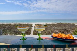 Two margarita glasses on a colorful table with a beach view in the background. - One NITE  MINIMUM  5 steps off deck onto beach; 10 steps out front door to pool. (Panama City Beach)