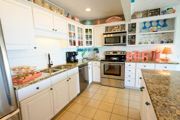 A kitchen with white cabinets, stainless steel appliances, and a granite countertop.
