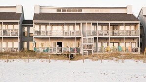 A row of multi-story buildings with balconies, a sandy foreground, and a clear sky. - One NITE  MINIMUM  5 steps off deck onto beach; 10 steps out front door to pool. (Panama City Beach)