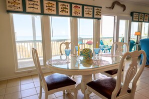 Enjoy meals with a view of the beach from this dining area, featuring a glass-top table and comfortable seating.