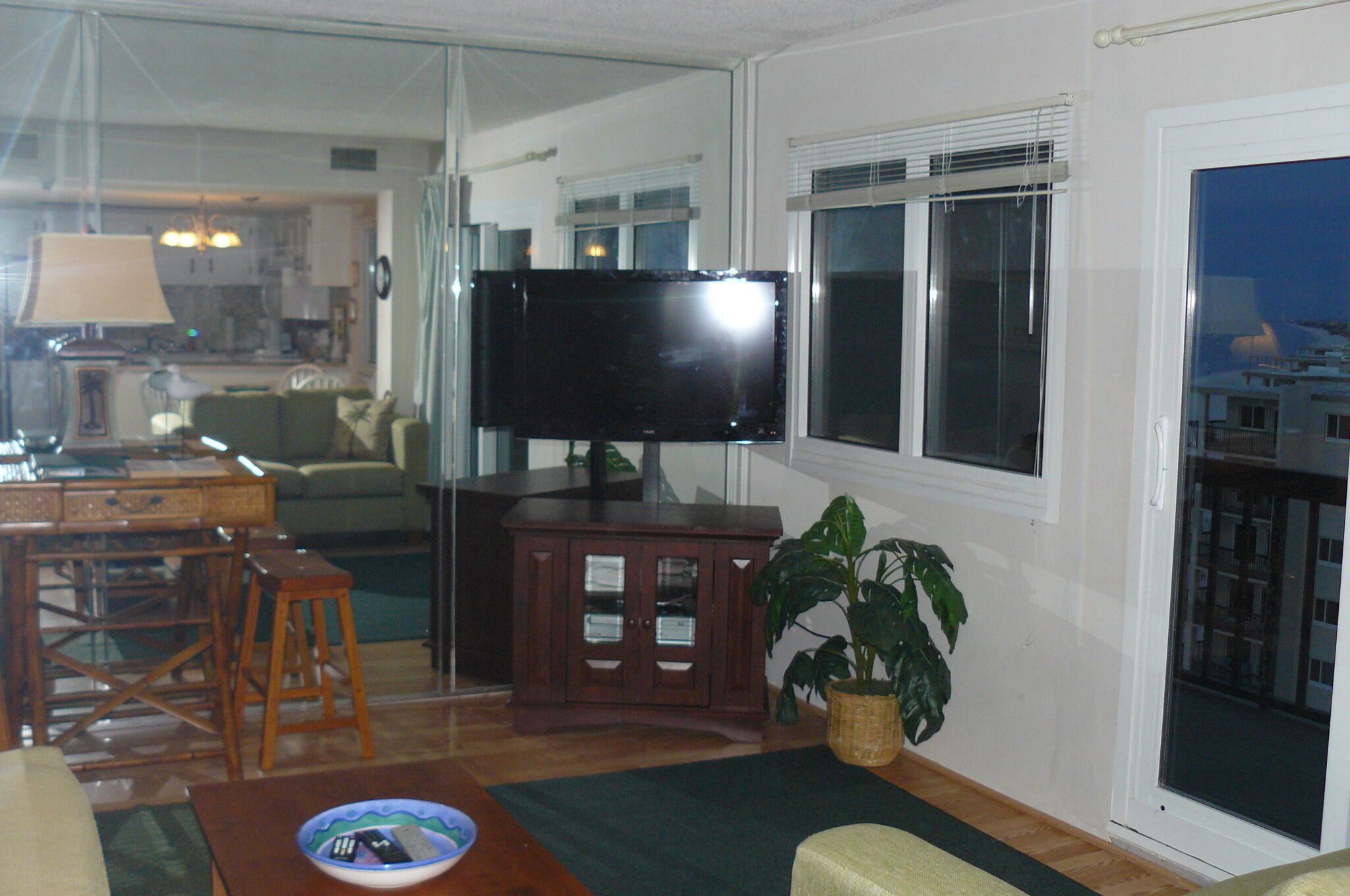 A living room with a television, a green sofa, a wooden coffee table, and a potted plant.