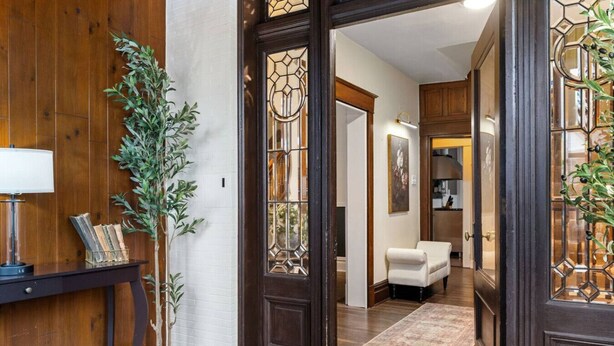A wooden interior with a white brick wall, a potted plant, a desk with a lamp, and a white armchair. - Family-Focused Victorian In Quiet Area, Pets OK, Yard & Parking (Pittsburgh)