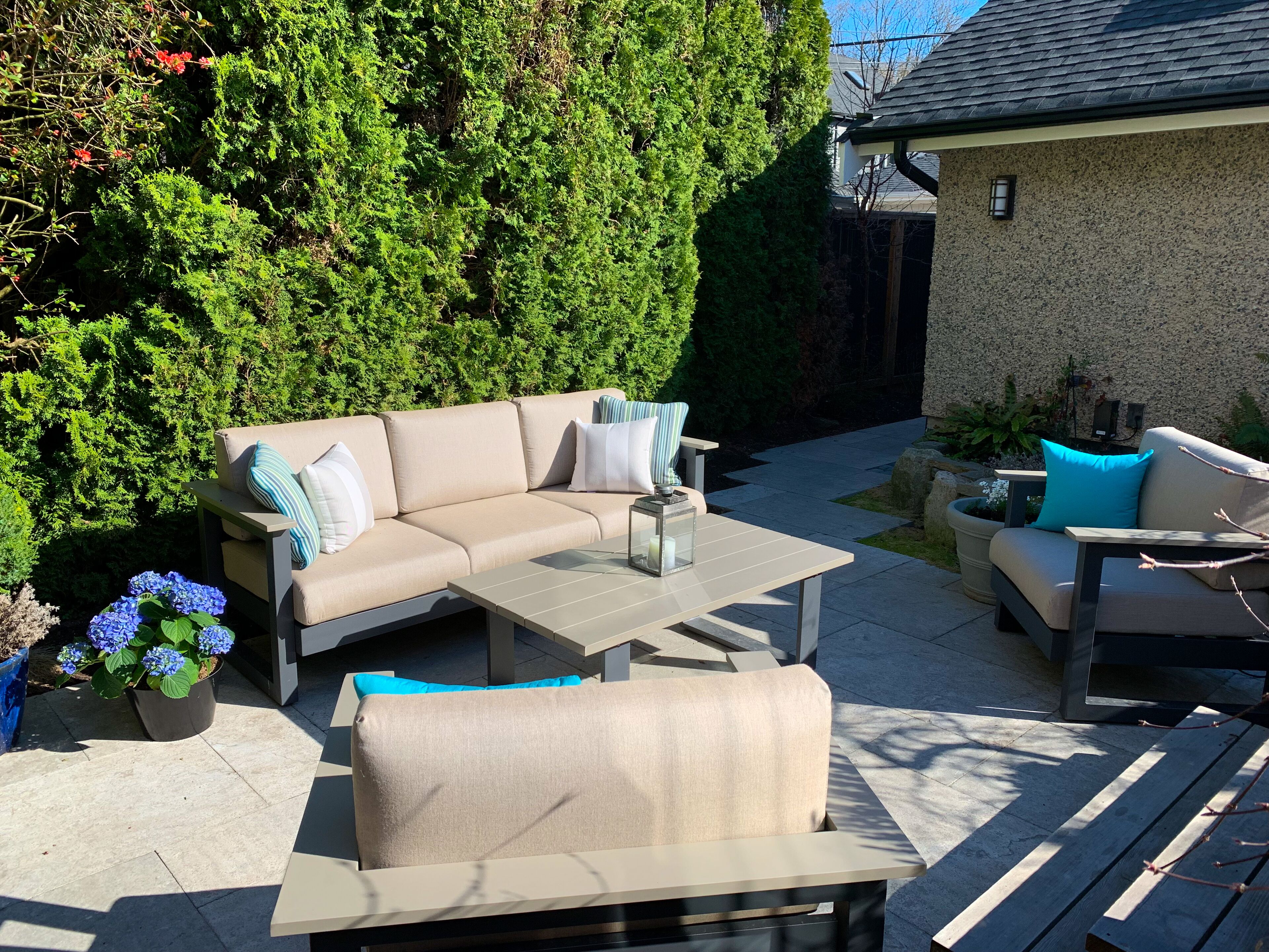 An outdoor patio area with a beige sofa, a matching armchair, and a small table.