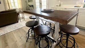 Una cocina con una isla central, taburetes de bar, ventilador de techo y un rincón comedor con sofá.