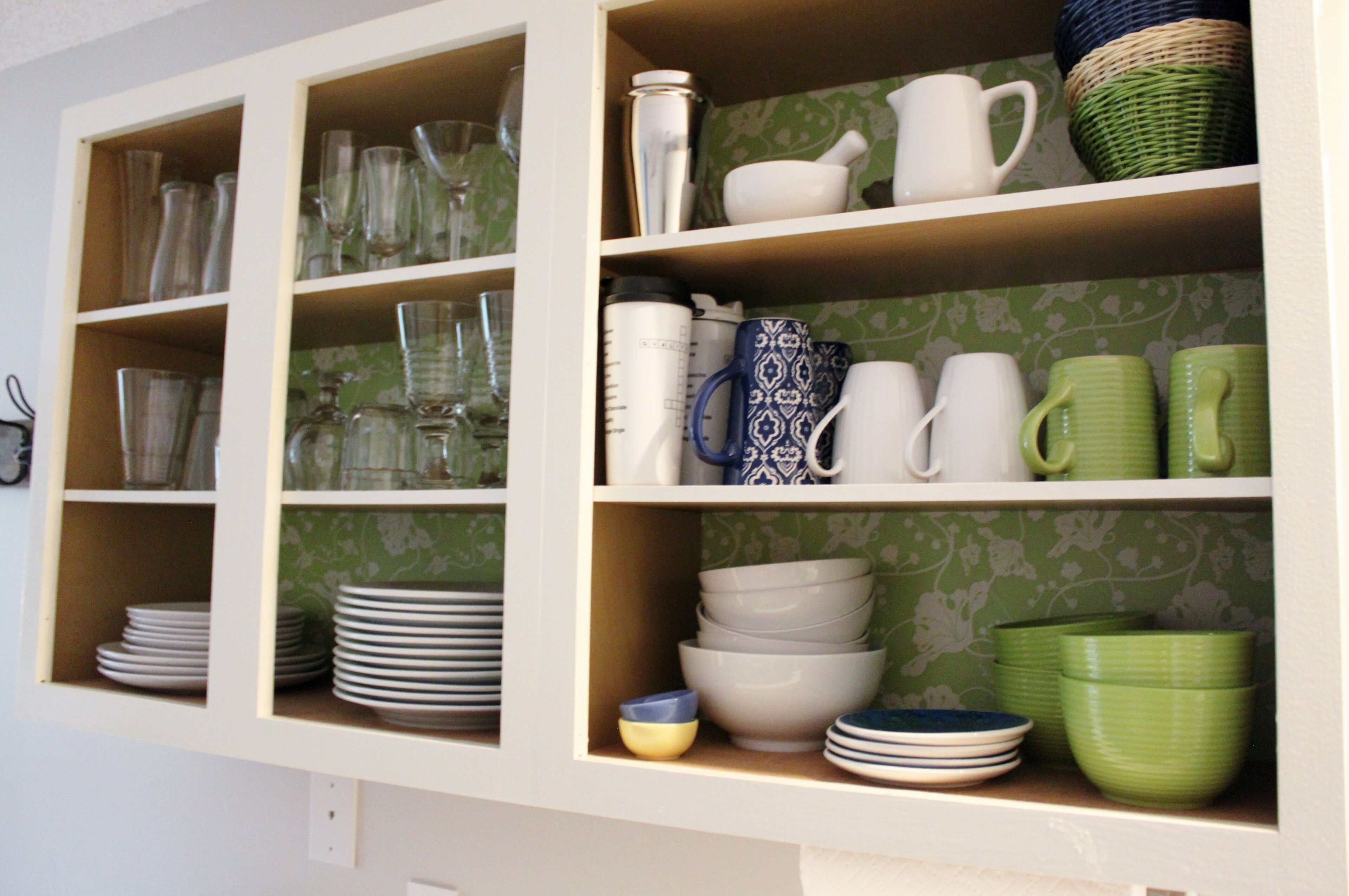 A kitchen with shelves containing various glassware, plates, and bowls.