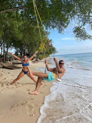 A beach with a swing set, sandy shore, and ocean view. - 'Cheez Don Bread' is a Beach Front Accommodation on Long Beach Barbados. (Christ Church)