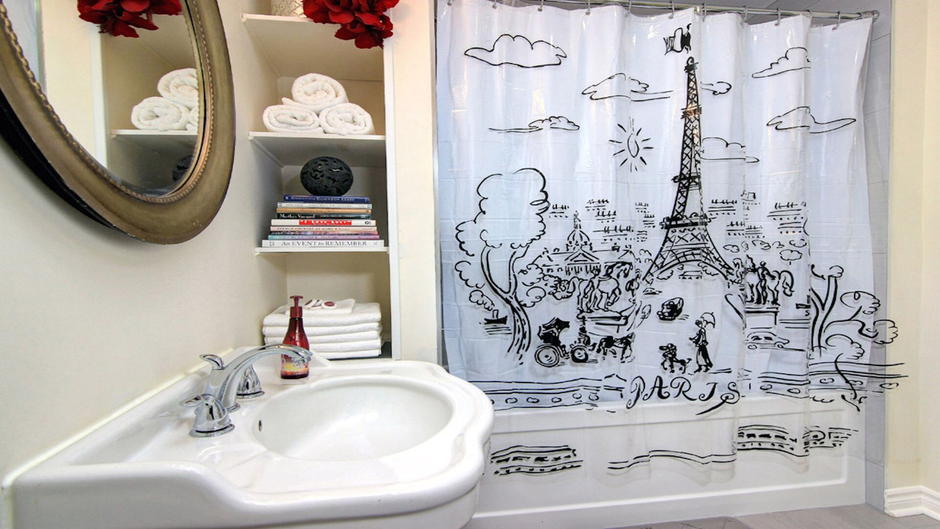 A bathroom with a white sink, a mirror, and a shower curtain depicting Paris landmarks.