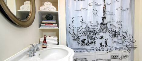 A bathroom with a white sink, a mirror, and a shower curtain depicting Paris landmarks.