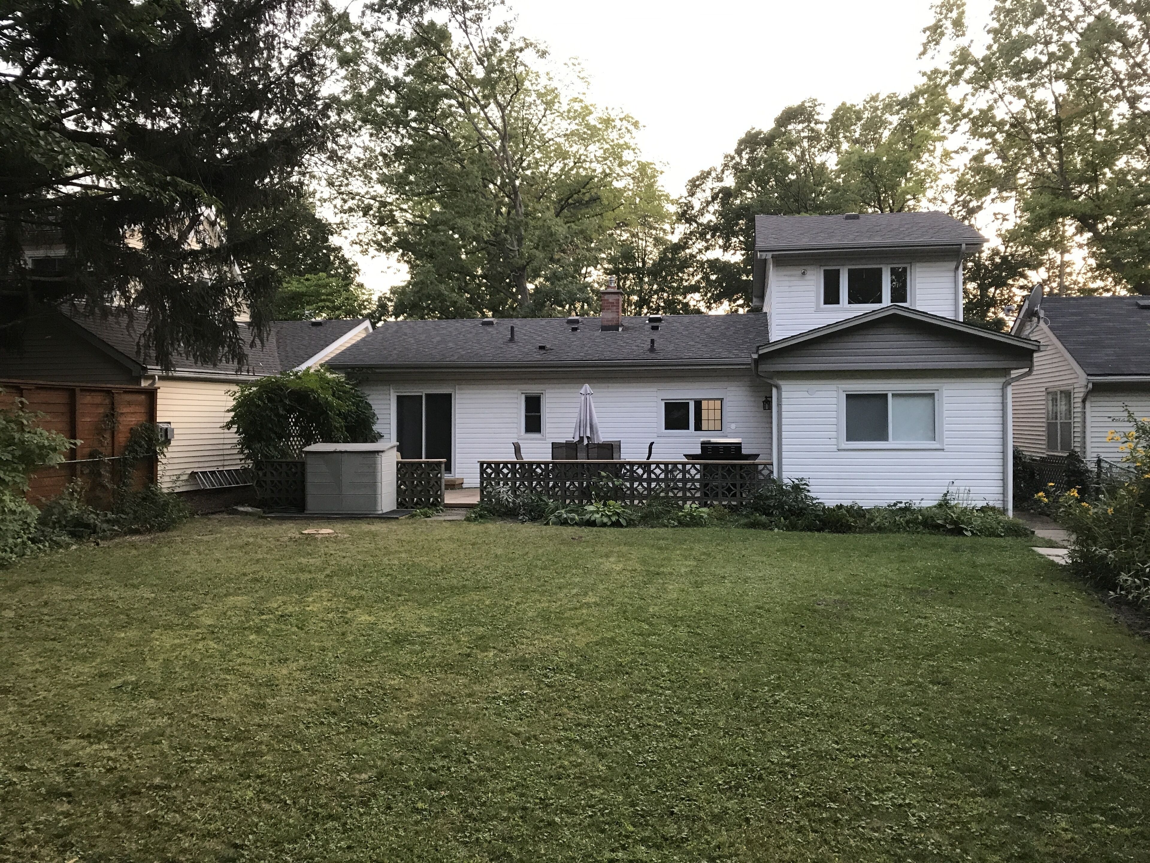 A two-story house with a front yard and a small patio area.