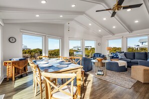 Un'ampia zona giorno con tavolo da pranzo, sedie in legno, divano e ventilatore a soffitto.