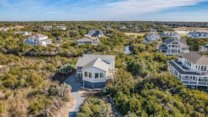 Una zona residenziale costiera con numerose case immerse nel verde sotto un cielo sereno.