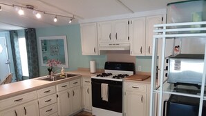 A kitchen with white cabinets, a stove, a sink, and a refrigerator.