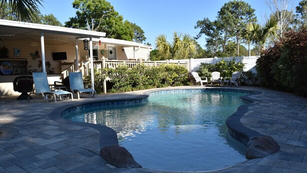 A swimming pool with lounge chairs and a covered patio area.
