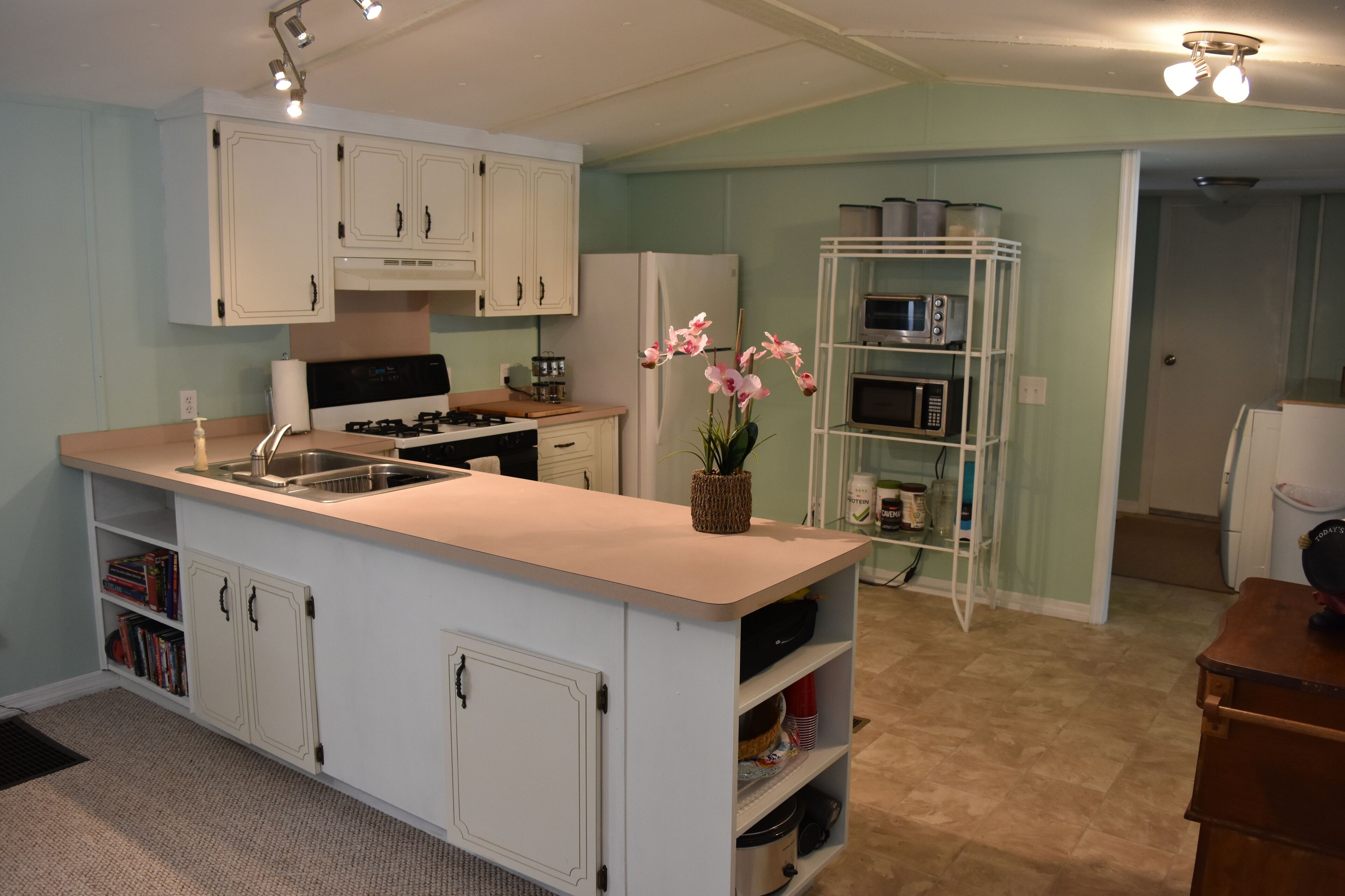 A kitchen with white cabinets, a central island, a stove, and a microwave.