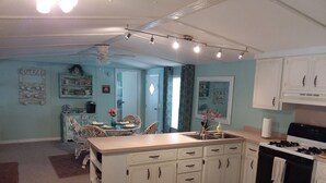 A kitchen with white cabinets, a stove, and a dining area with a table and chairs.