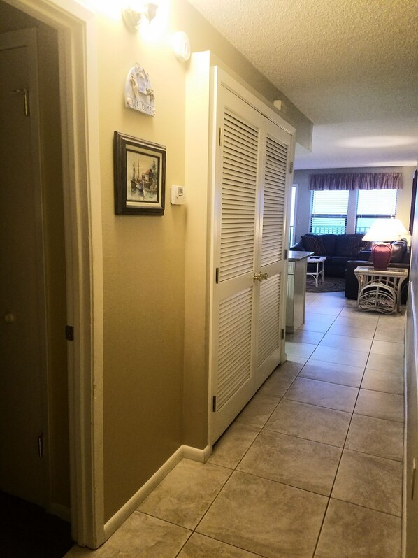 A hallway with a closed door, a framed picture, a thermostat, and a window with blinds.