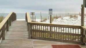 Un muelle de madera que lleva a una playa con un letrero.