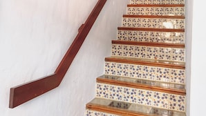 Una escalera con baldosas estampadas y barandilla de madera.