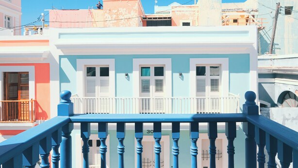 Un edificio de varios pisos con barandal de balcón y una puerta.