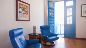 Una habitación con dos sillones de cuero azul, una mesita de madera y un cuadro en la pared.