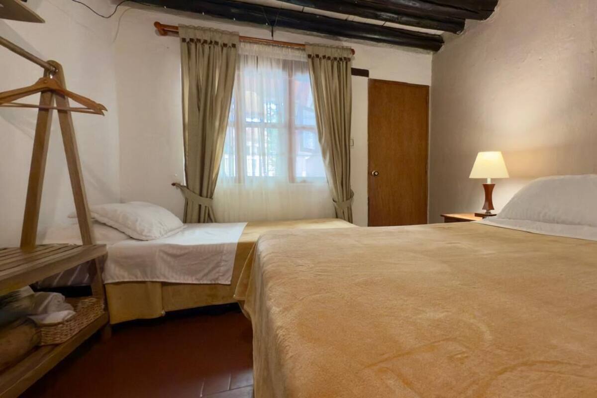 A room with two beds, a wooden wardrobe, a mirror, and a lamp.