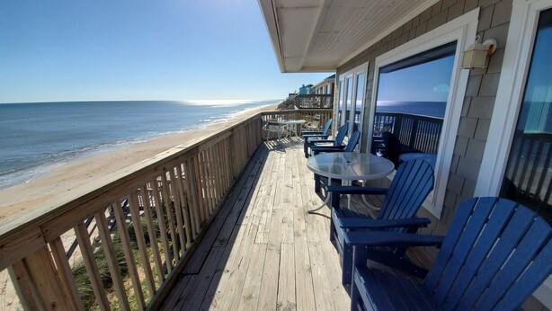 A wooden deck with a glass balustrade overlooking a beach. - Oceanfront House with Private Beach, Patio, and Gameroom (Ponte Vedra Beach)