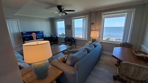 A living room with a sofa, a coffee table, a TV, and a view of the ocean. - Oceanfront House with Private Beach, Patio, and Gameroom (Ponte Vedra Beach)