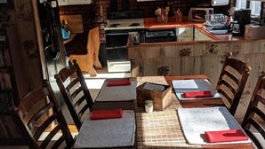 Une cuisine chaleureuse avec des meubles en bois, une table à manger entourée de chaises et un lustre.