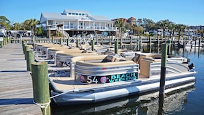 A marina with several boats docked, a wooden pier, and a building with a sign that reads "BEACH WEEKEND".