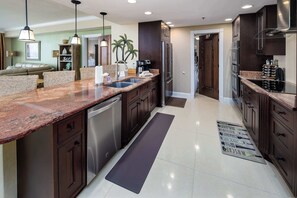 A modern kitchen with dark wood cabinets, stainless steel appliances, and a granite countertop.