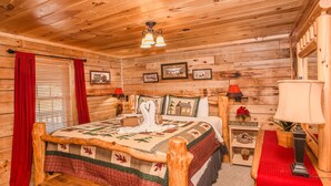 Ein Schlafzimmer in einer Holzhütte mit einem Bett, einer Bank, einem Nachttisch und einer Lampe.