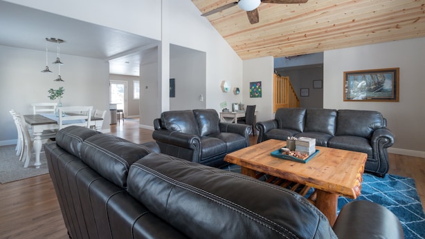 A spacious living area with leather sofas, a wooden coffee table, and a ceiling fan. - Beautiful Home in McCall w/ family & living room and large backyard w/ firepit (Mccall)