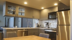 Une cuisine moderne équipée d’appareils électroménagers en acier inoxydable, d’une table à manger en bois et d’un four à micro-ondes encastré.