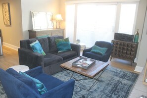 Ein Wohnzimmer mit einer Couch, Sesseln, einem Couchtisch und einem Beistelltisch.