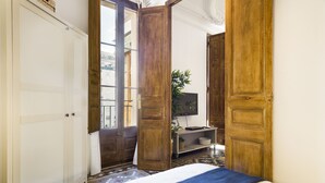 A bedroom with a bed, wooden wardrobe, and a television on a stand. - The Classic Apartment (Barcelona)
