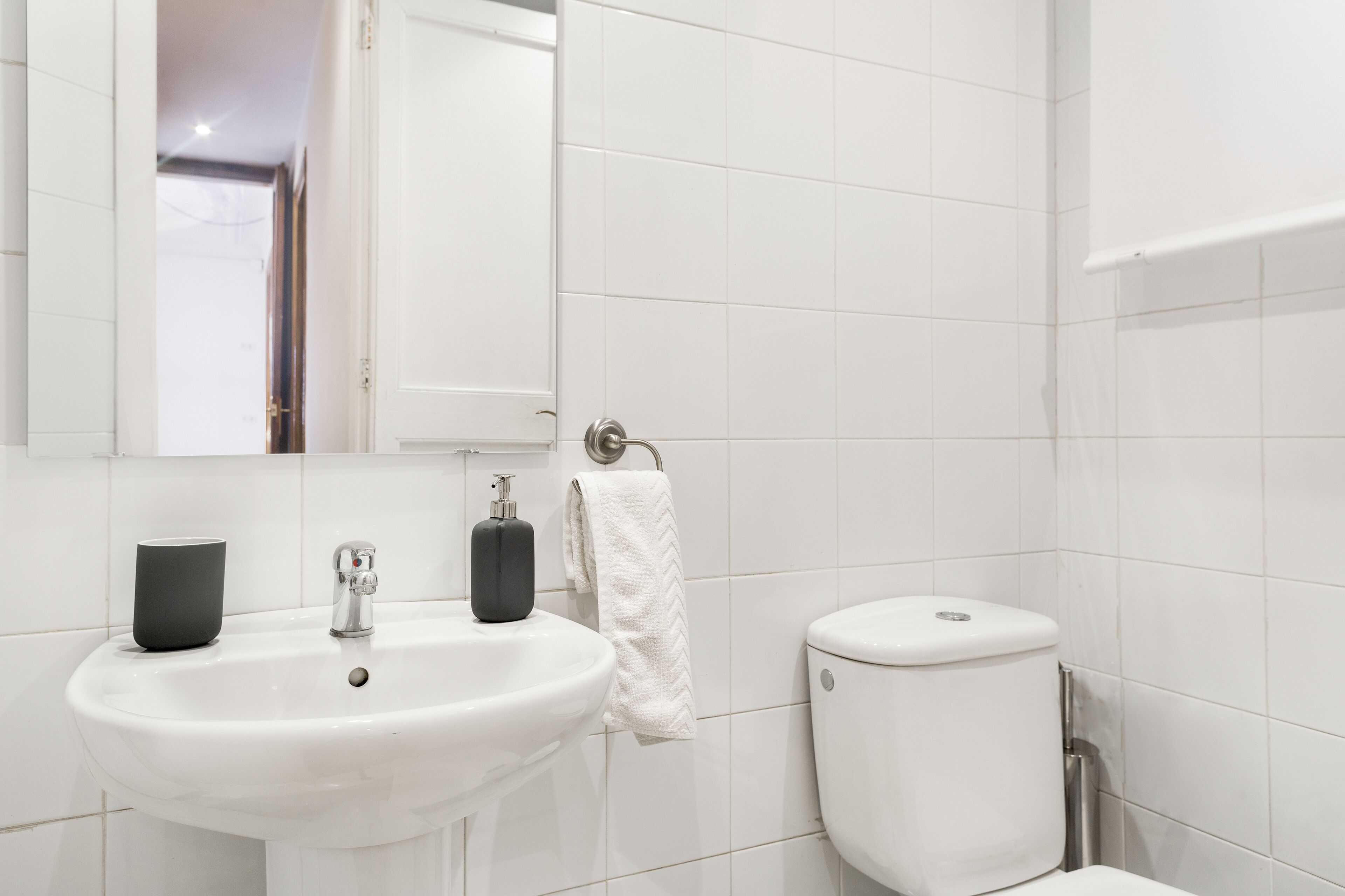 A modern bathroom with a white sink, a mirror, and a toilet.