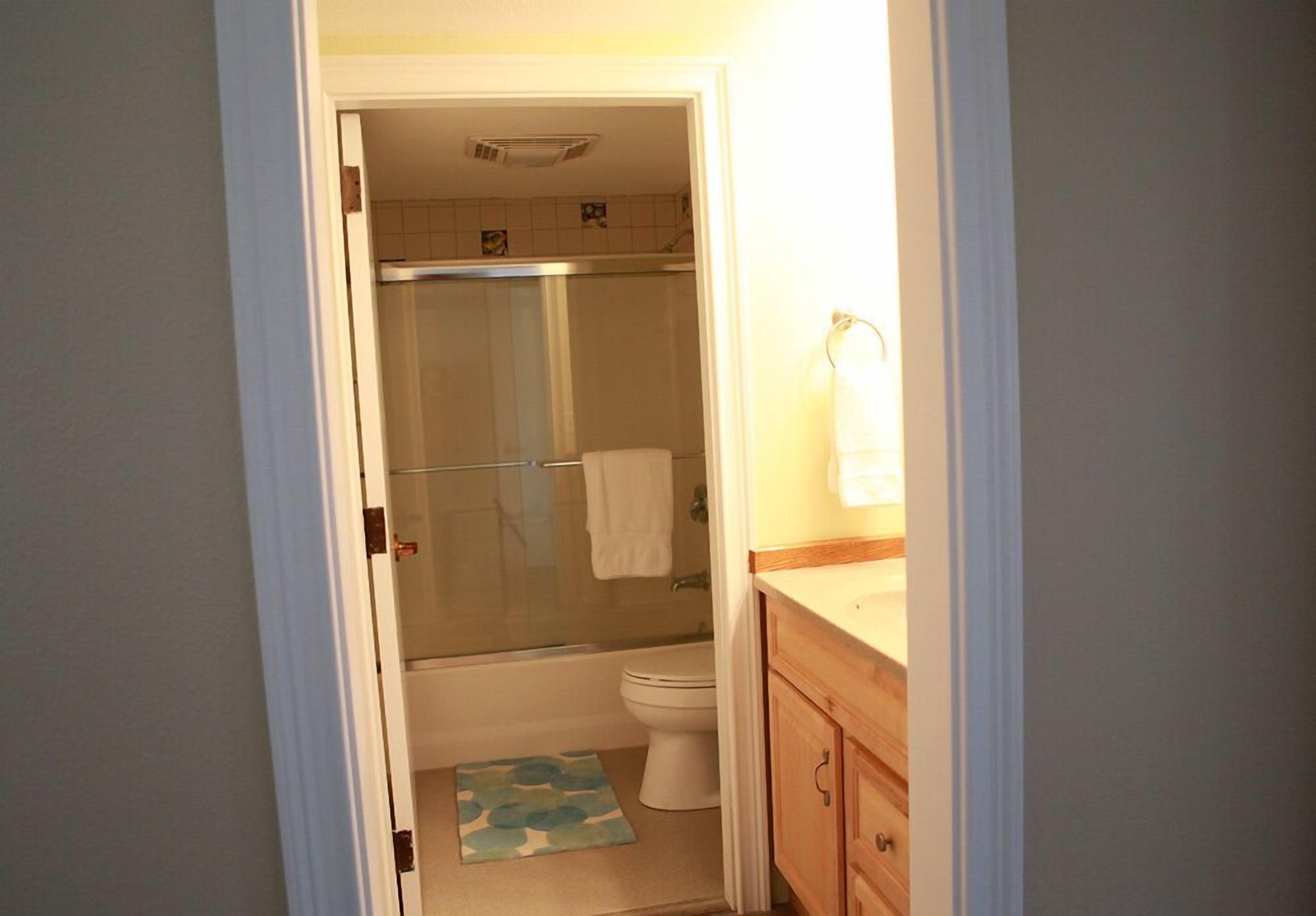 A bathroom with a glass-enclosed shower, a toilet, and wooden cabinets.