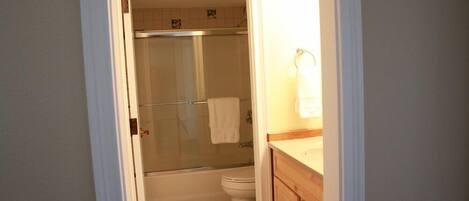 A bathroom with a glass-enclosed shower, a toilet, and wooden cabinets.