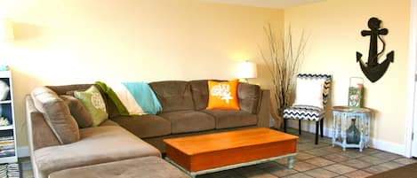 A living room with a brown sofa, a wooden coffee table, and a decorative anchor on the wall.