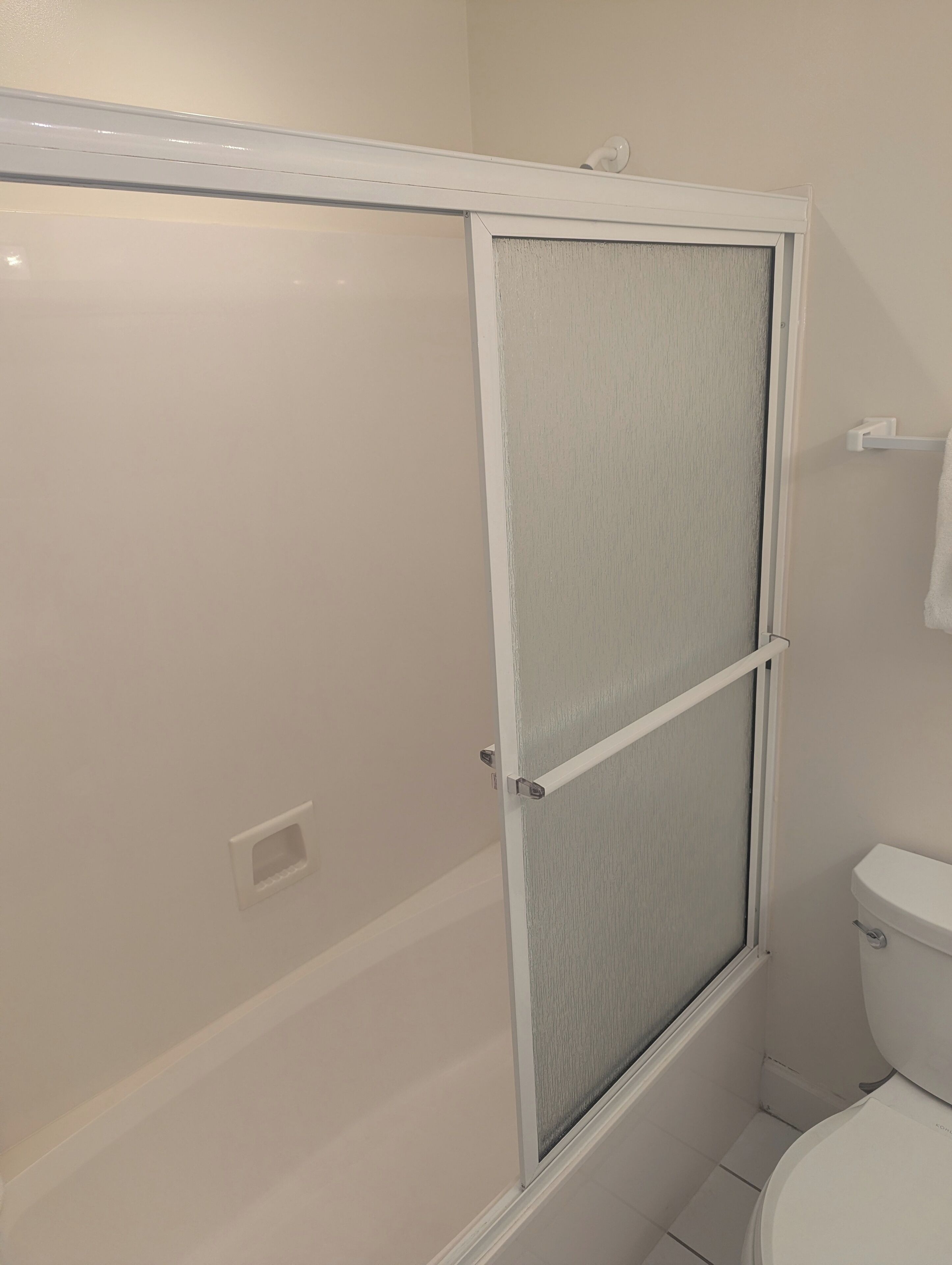 A bathroom with a shower enclosure, a toilet, and a towel rack.