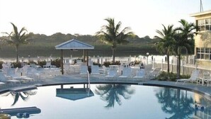 A pool area with lounge chairs and umbrellas, surrounded by palm trees and a white fence. - 5 STAR RATED, GREAT PRICES NEW FULLY RENOVATED IS WAITING FOR YOU 3 BEDROOM E112 (Indian Shores)