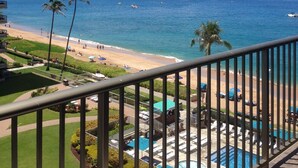 Un balcon avec vue sur une plage, une piscine et une montagne au loin.