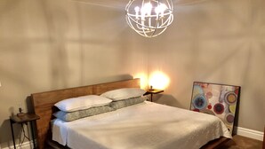 Un lit bien fait, avec une tête de lit en bois, une table de chevet avec une lampe et un luminaire fixé au mur.