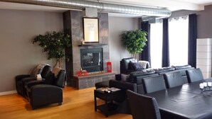 Een moderne woonkamer met een open haard, lederen meubels en een groot raam.